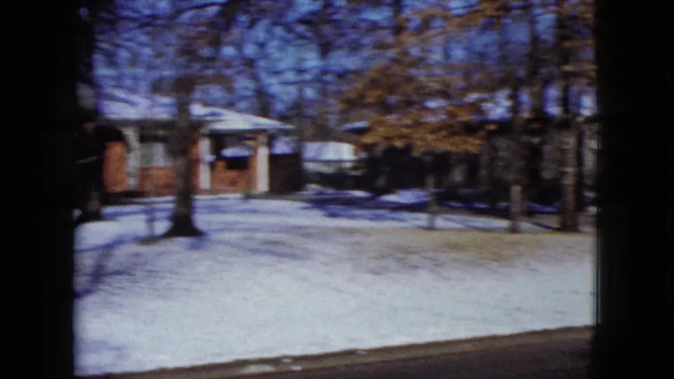 1960 Madison, Wisconsin winter neighborhood view with snow on lawns, bare trees, and low houses near the road.