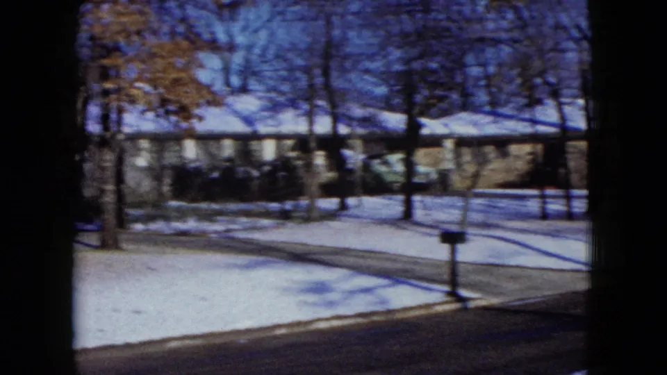 1960 Madison, Wisconsin frame with a roadside mailbox, snowy lawn, bare trees, and a single-story home across the street.