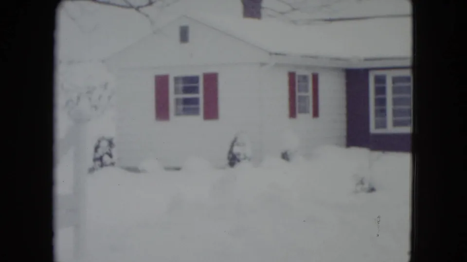 A Madison house with red shutters appears partly washed by bright snow exposure in this 1960 winter home-movie frame.