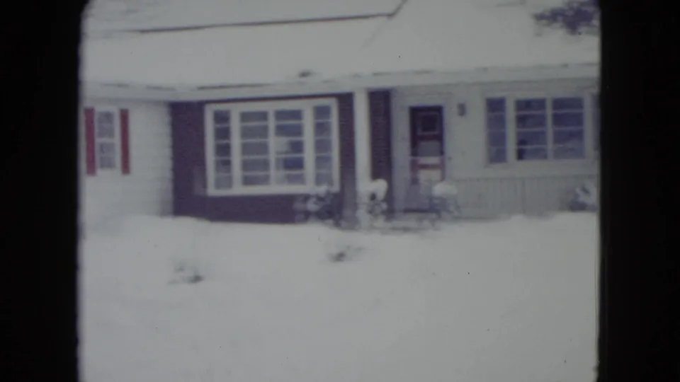 Front view of a single-story Madison residence in snow, showing wide windows, red shutters, a doorway, and a buried yard.