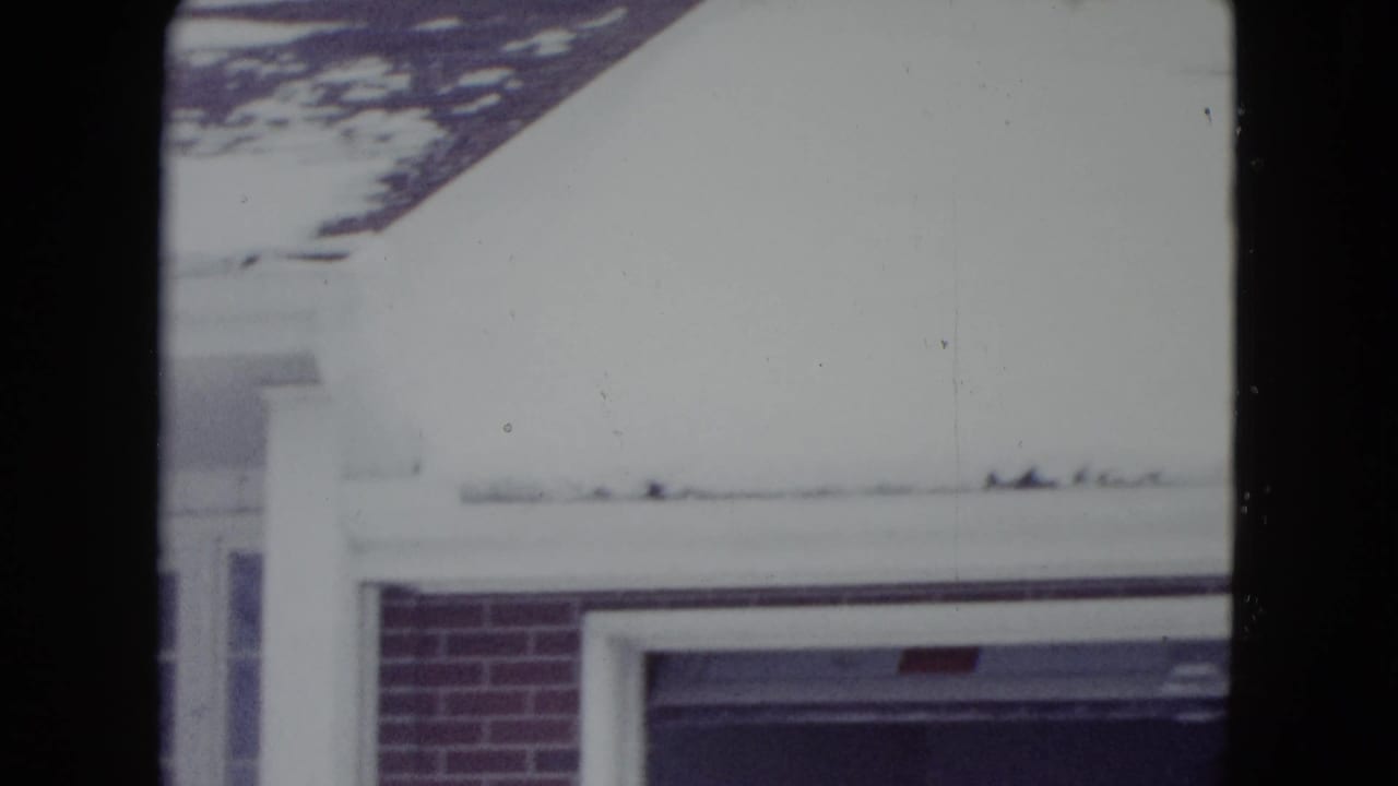 Snowy exterior with part of a brick building and dark film frame divisions.