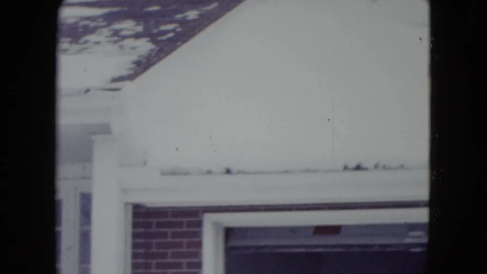 1960 Madison 8mm frame showing a snow-covered building edge before the tractor action enters view.