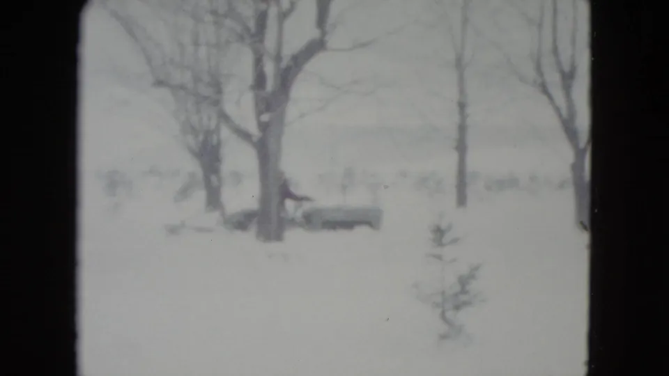 The final frame holds on a snow-covered rural area in Madison, Wisconsin, with leafless trees and small evergreens after the tractor has passed.