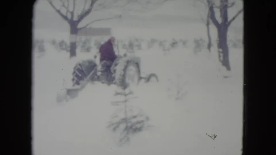 The distant driver continues across the Madison winter field on a tractor fitted with a snow blade.