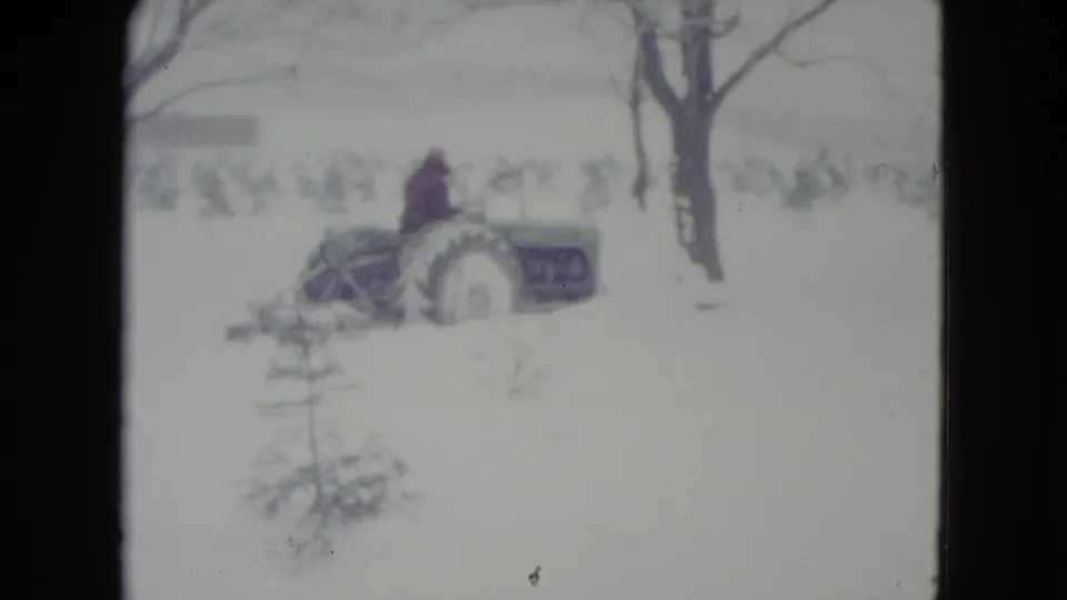 The clip ends with the tractor still moving through the snowy Madison field, framed by bare trees.
