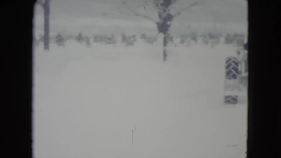 The tractor is partly out of frame at the edge of a Madison winter field, leaving mostly deep snow and bare trees visible.
