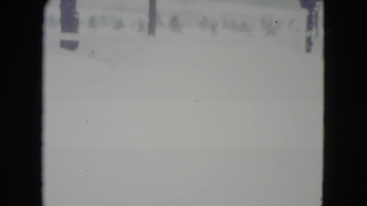 1960 Madison, Wisconsin 8mm frame showing a pale snow-covered field with faint trees or poles near the horizon.