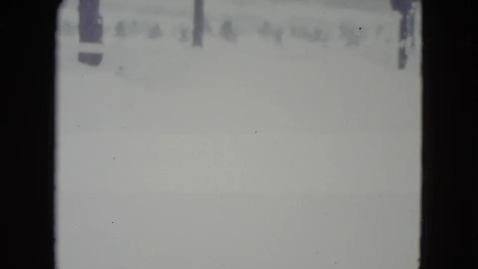 1960 Madison, Wisconsin 8mm frame showing a pale snow-covered field with faint trees or poles near the horizon.