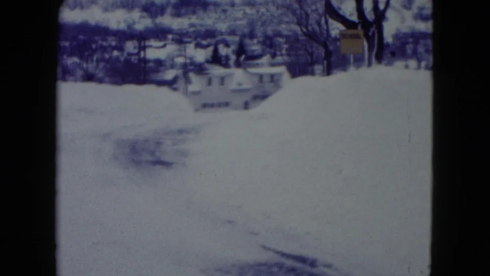 1960 Madison, Wisconsin street view with heavy snowbanks, distant houses, and bare winter trees in soft 8mm color.