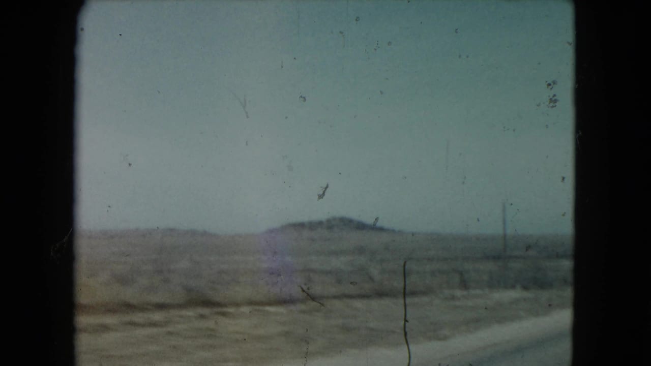 Desert landscape and road seen through a grainy 8mm film frame.