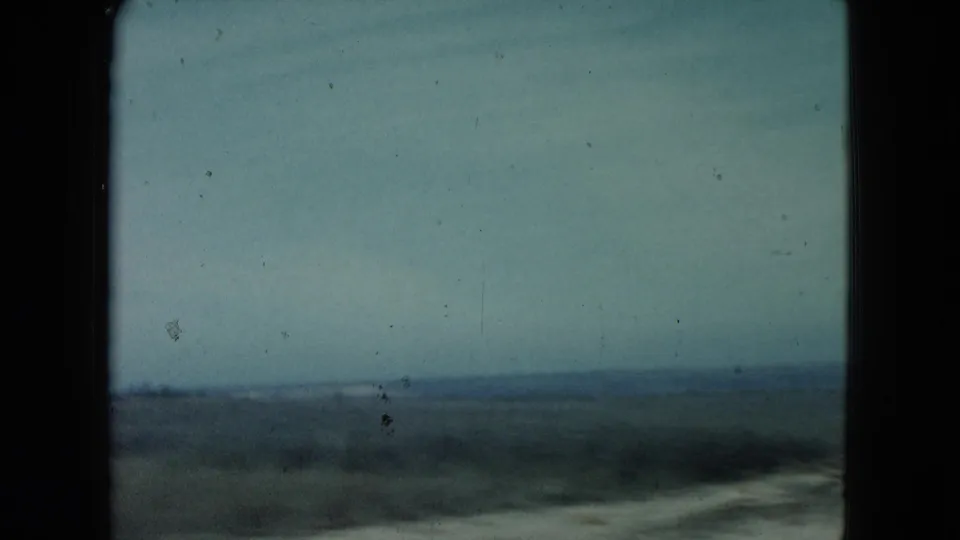 1960 Nevada home-movie frame showing a blurred roadside landscape and distant horizon from a moving car.