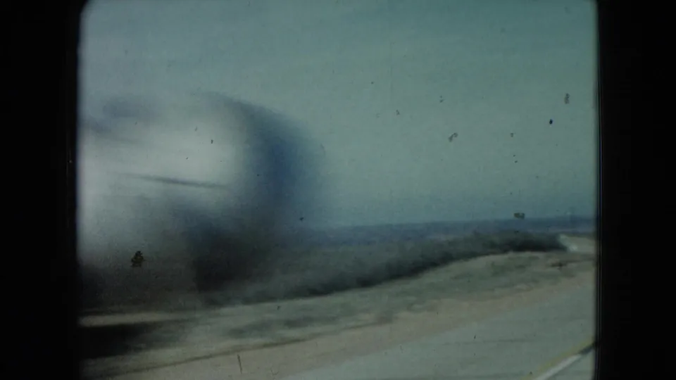 A period car passes close to the filming vehicle during a 1960 Nevada road-trip shot across open countryside.