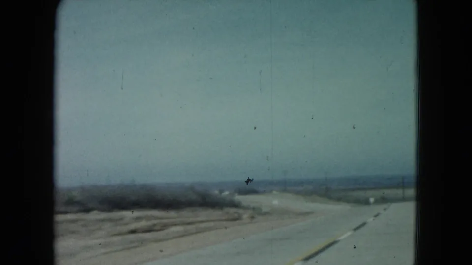 1960 Nevada home-movie view of an empty rural highway receding through sparse open terrain.