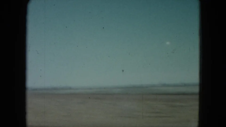 1960 Nevada 8mm frame showing a wide, empty plain with a hazy low horizon and soft film grain.
