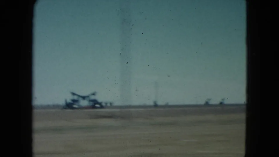 1960 Nevada roadside view with a blurred aircraft-like silhouette and small distant forms across a flat open field.