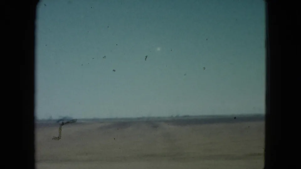 1960 Nevada home-movie frame showing an open, sparsely detailed field and pale sky from a moving vehicle viewpoint.