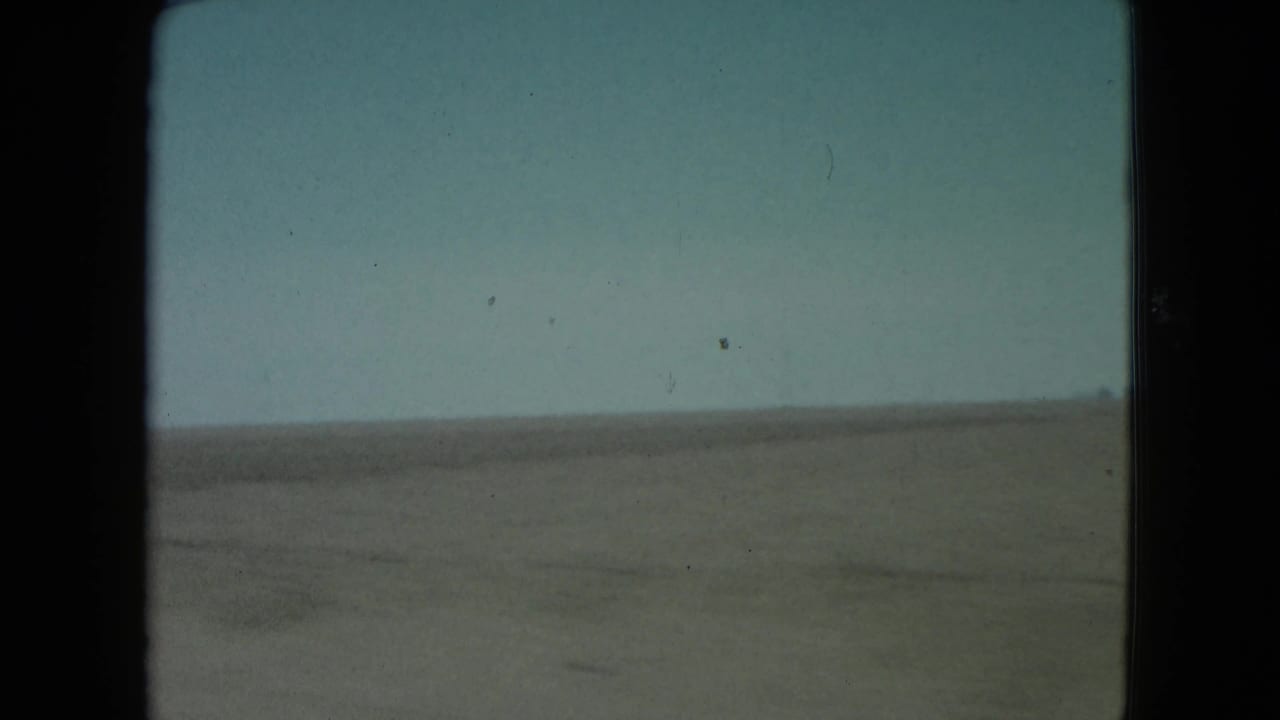 Barren desert plain and pale sky seen through a dark film frame.