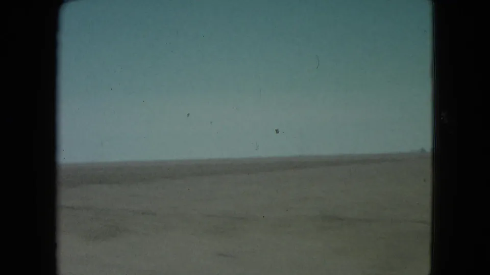 1960 Nevada 8mm view of open sandy terrain and a low horizon, with no people, vehicles, or buildings visible.
