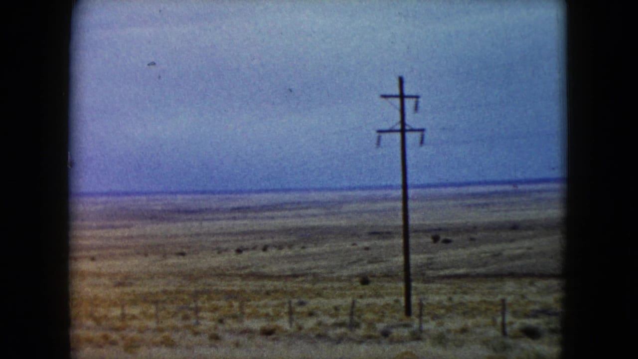 Utility pole standing in open desert with low scrub and distant horizon.