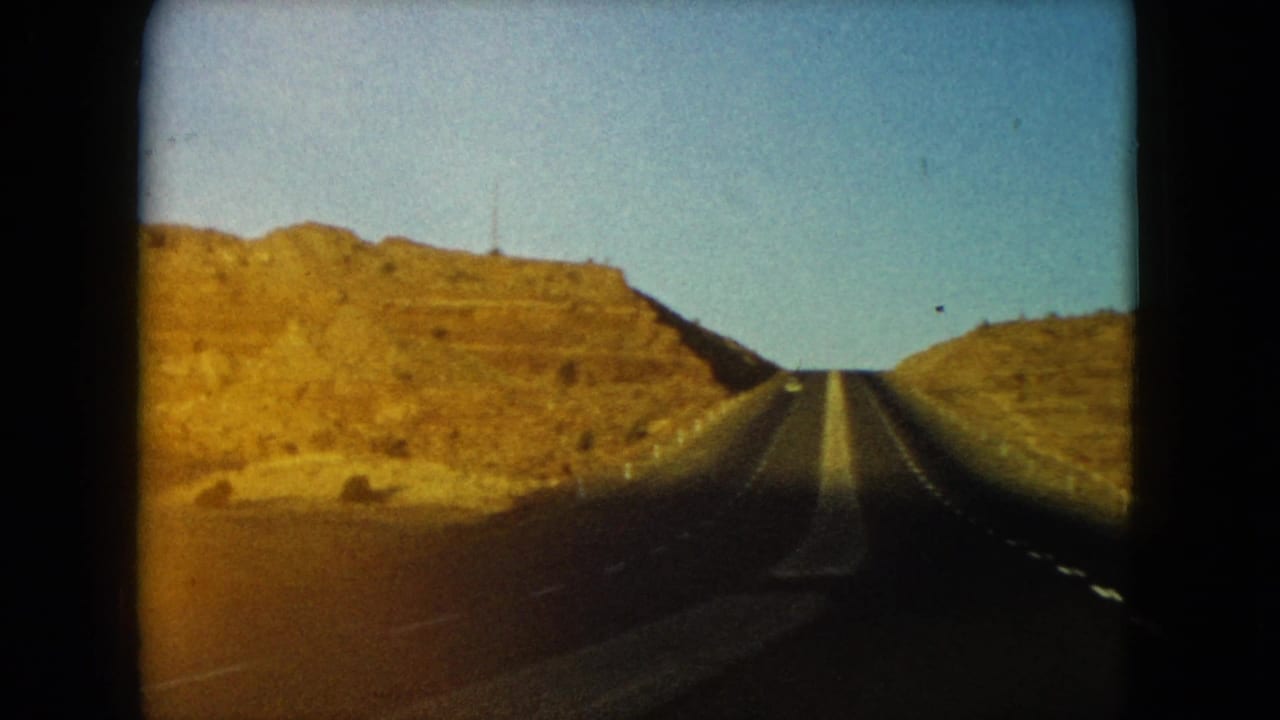Straight highway rising between dry hills under a clear sky.
