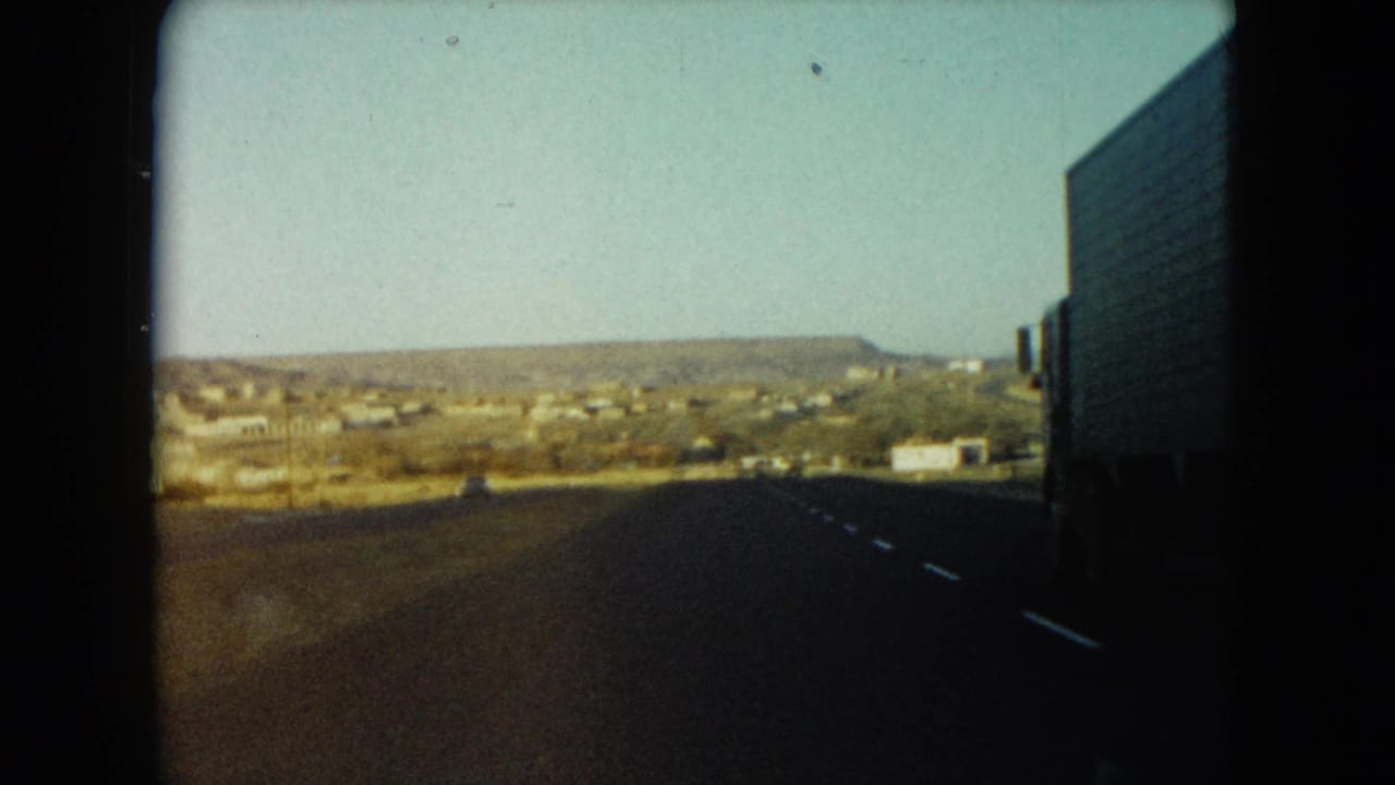 Highway view with distant settlement and a large truck along the right edge.
