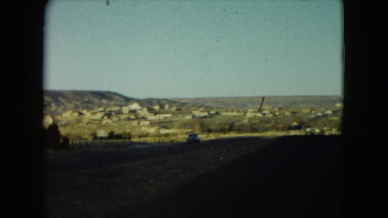 1960 Nevada roadside view of low buildings and hills beyond a shadowed highway foreground.