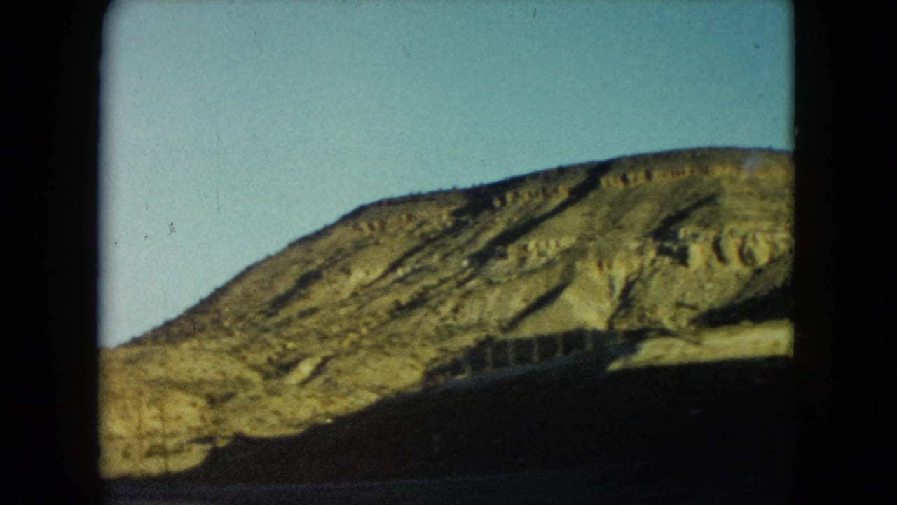 Rocky hillside beside a roadway under a clear blue sky.