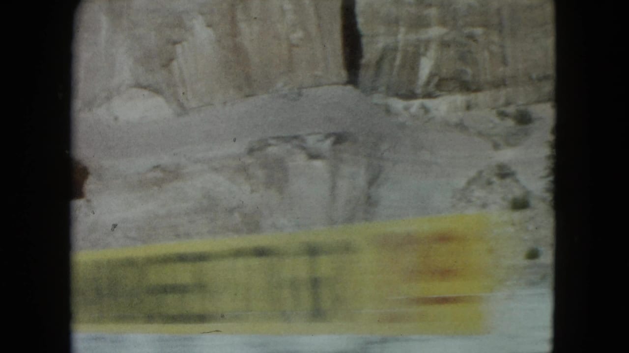 Yellow roadside barrier passing in front of a rocky desert wall.