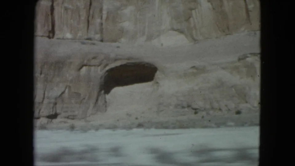 A pale desert rock wall and roadside edge appear in soft 8mm footage from a Nevada road trip.
