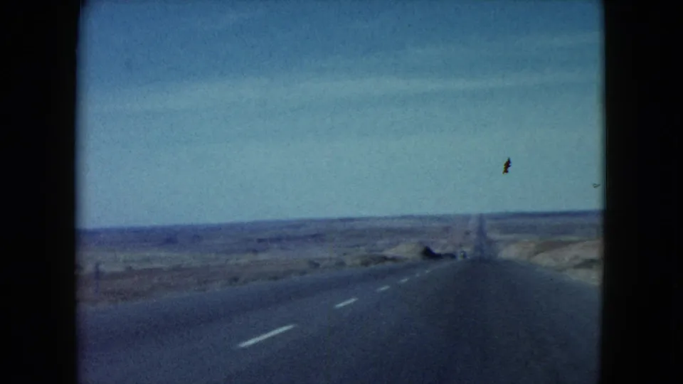 1960 8mm view from a moving vehicle on a long desert highway in the American Southwest.
