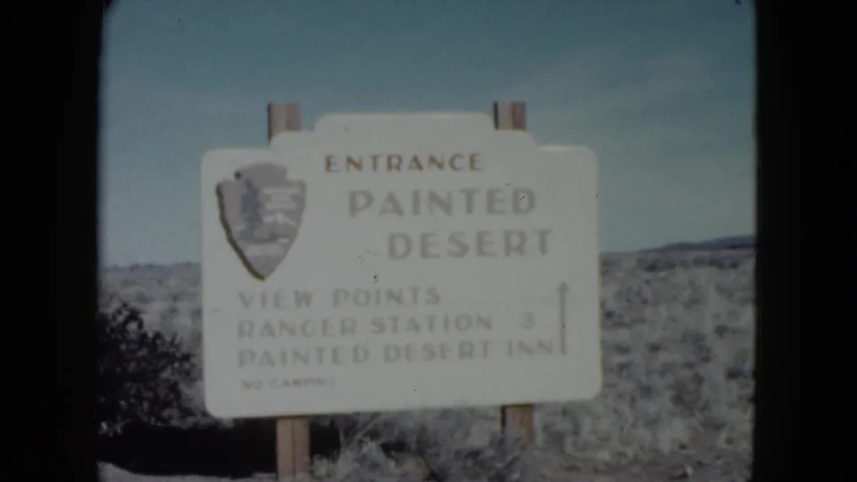 Painted Desert entrance sign filmed on 8mm, with text for view points, ranger station, and Painted Desert Inn visible.
