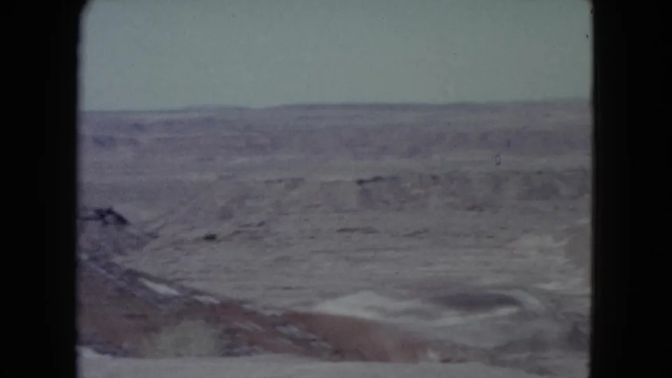 Nevada 8mm travel footage frame with open scrubby terrain, distant horizon, and muted mid-century color fading.