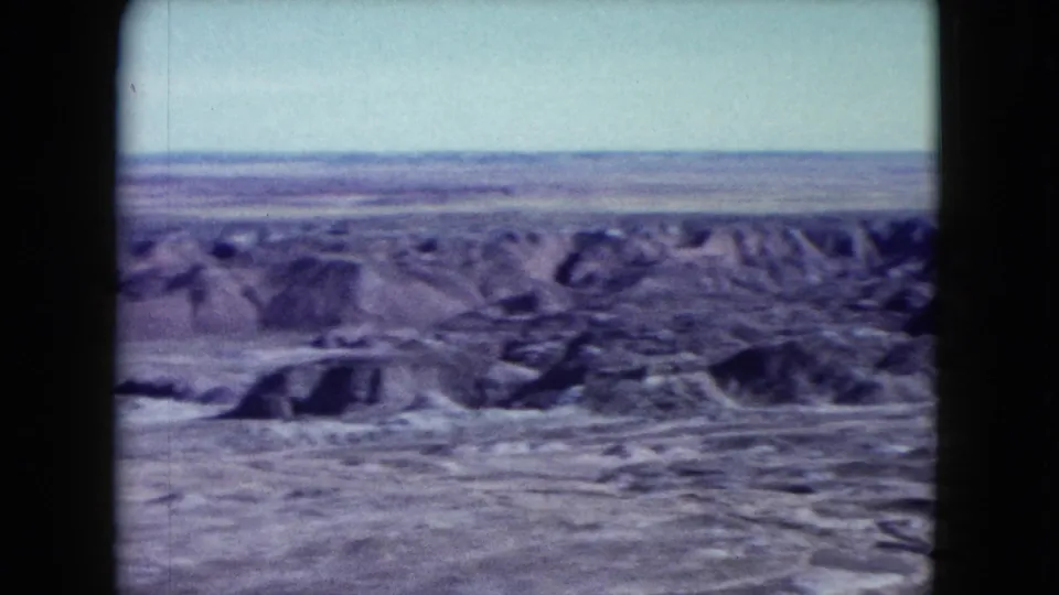 The final 1960 Nevada 8mm frame shows a horizontal canyon panorama with rugged eroded hills and a pale distant horizon.