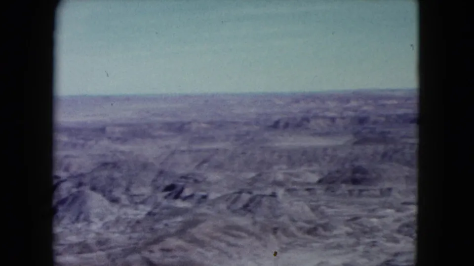 1960 Nevada 8mm panorama with foreground ridges, open desert, and a pale sky.