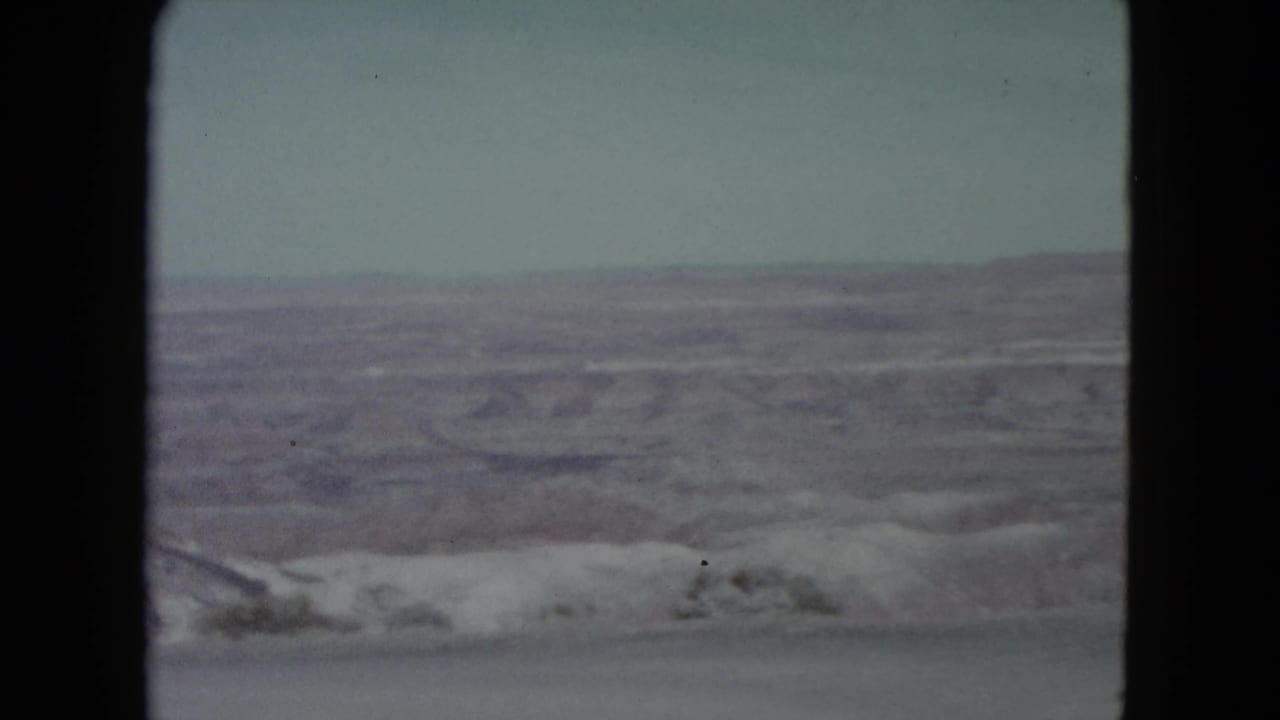 Static canyon view with layered rock formations and pale sky inside 8mm borders.