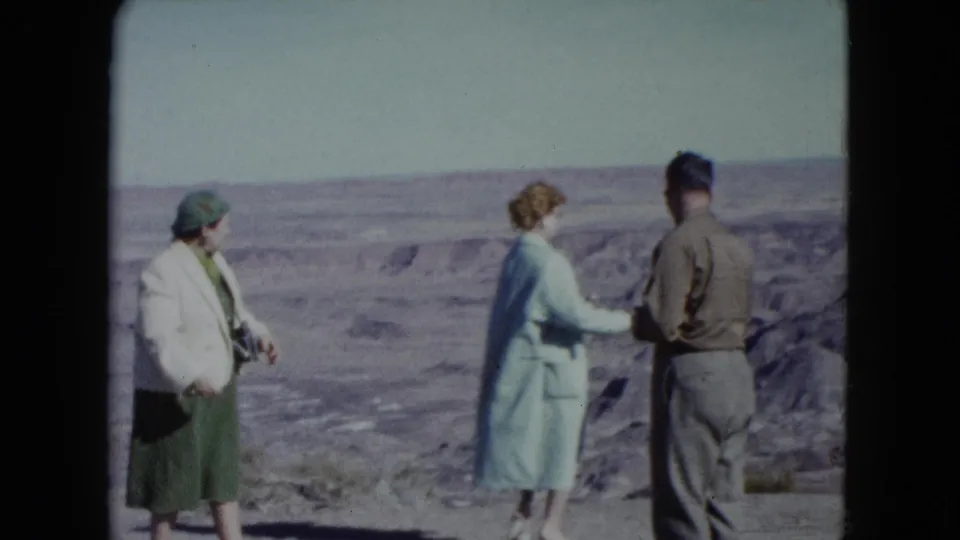 The final frame shows the woman in the light blue coat turned toward the man, with the other woman standing back at the Nevada overlook.