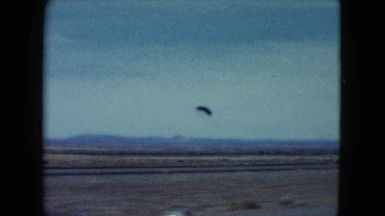 Open plain and distant hills seen through a dark car-window frame.