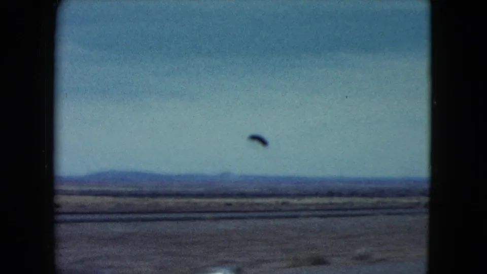 1960 Nevada landscape footage showing open plains, distant low hills, pale sky, and dark window framing from a moving car.