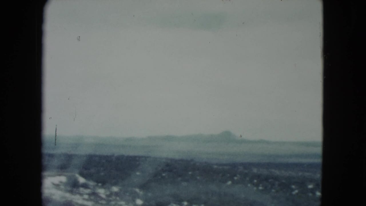 1960 Nevada travel frame with distant mountains, low desert terrain, pale sky, and soft 8mm fading.