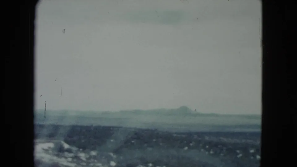 1960 Nevada travel frame with distant mountains, low desert terrain, pale sky, and soft 8mm fading.