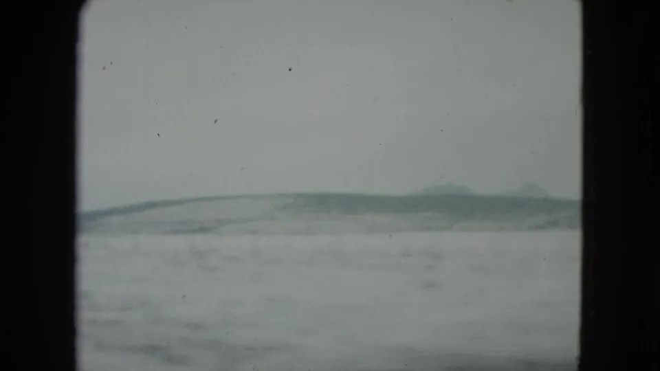 1960 Nevada 8mm frame showing snow-covered terrain and soft distant hills beneath an overcast sky.