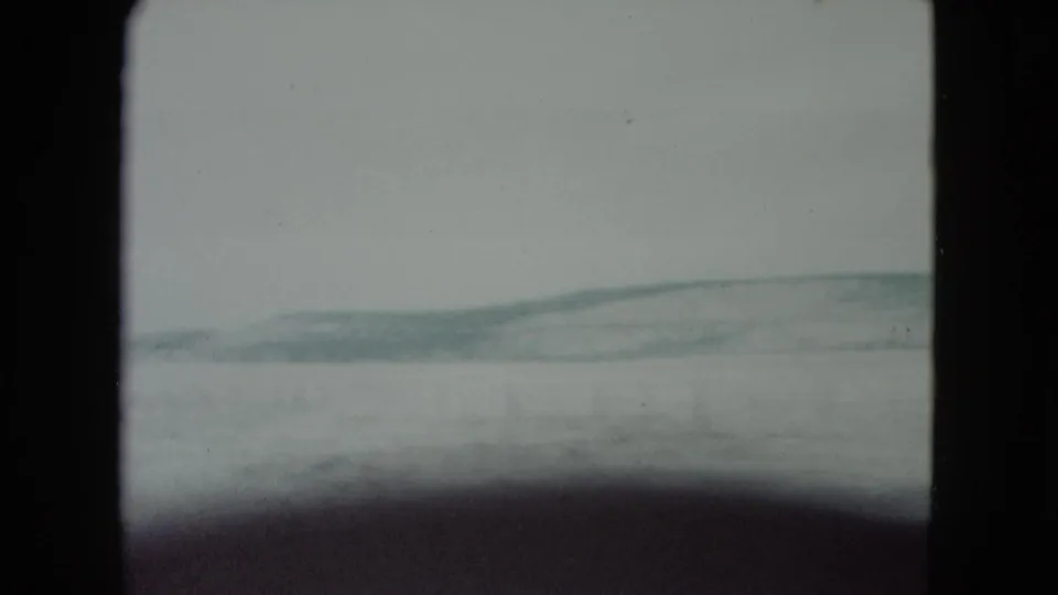 1960 Nevada 8mm still with a low ridge crossing the snowy horizon and a dark shape along the lower frame.
