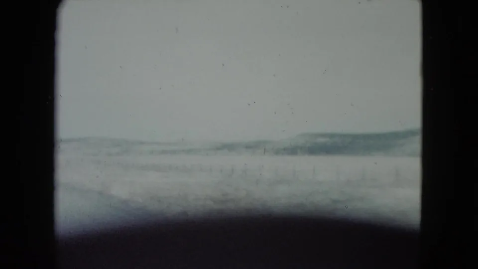 1960 Nevada home-movie view from a moving vehicle across flat arid land toward distant low hills.