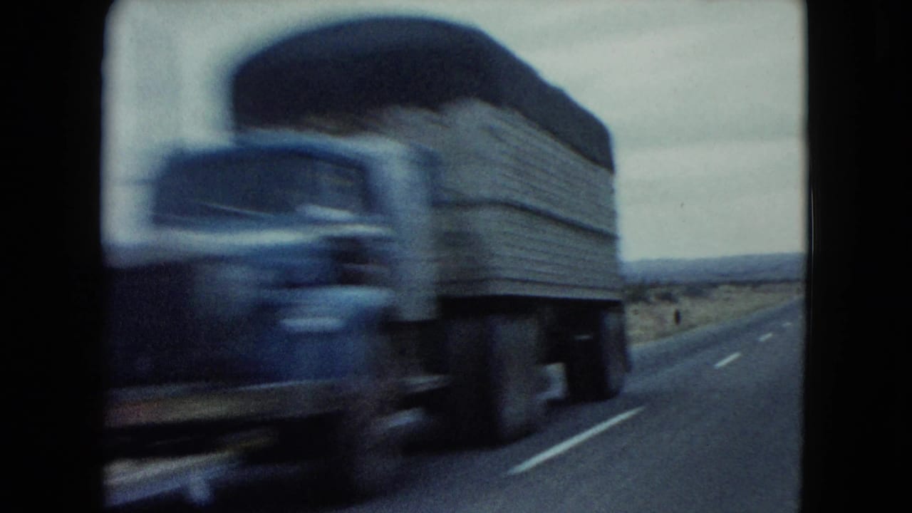 A motion-blurred older truck passes close to the camera on a Nevada desert highway in 1960 home-movie footage.