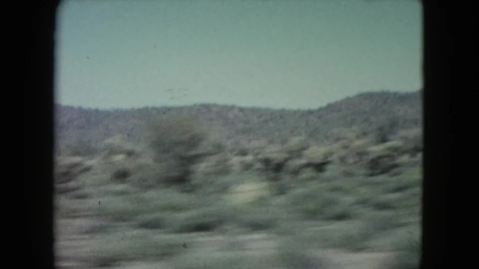 1960 8mm view of Nevada desert vegetation and low hills passing quickly through a dark-edged frame.