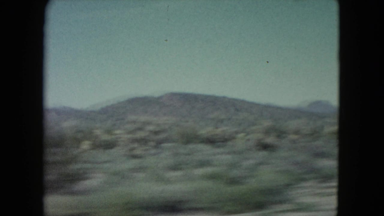 Nevada desert ridge and roadside scrub move laterally across a soft, grainy 1960 8mm frame.