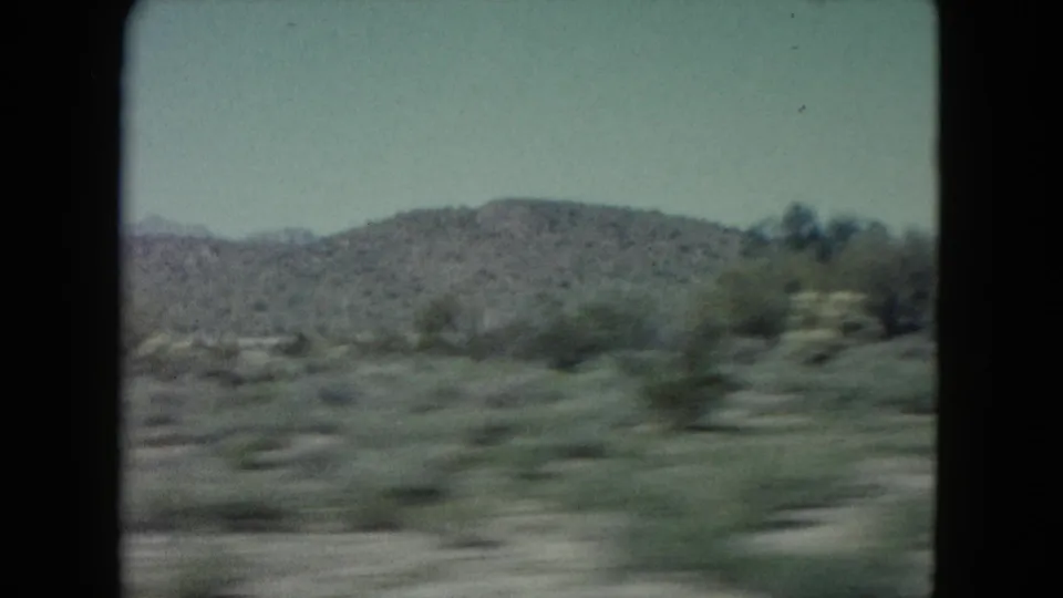 Fast-moving 8mm view of desert bushes, open ground, and distant hills in Nevada.