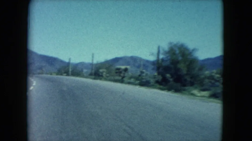 Nevada 8mm highway view showing an empty road through desert vegetation toward low mountains.