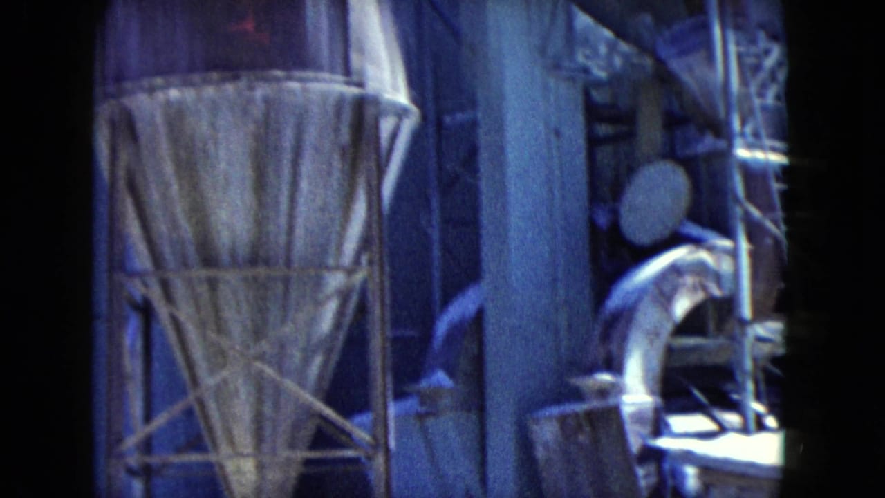 1960 Nevada industrial frame showing a conical hopper, scaffold supports, wall panels, and metal ducting in blue-shifted 8mm footage.