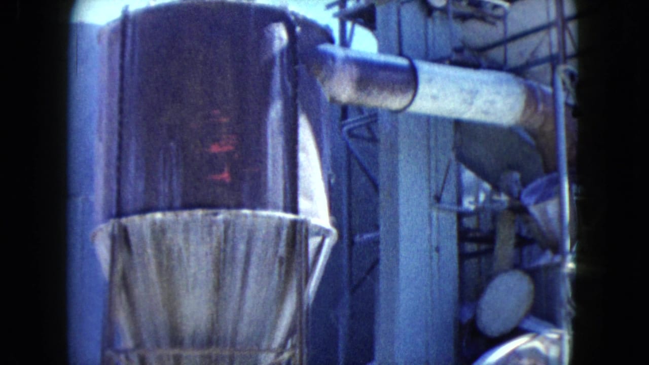 1960 Nevada factory frame with a tall conical hopper, horizontal pipe, surrounding machinery, and dense scaffolded structure.